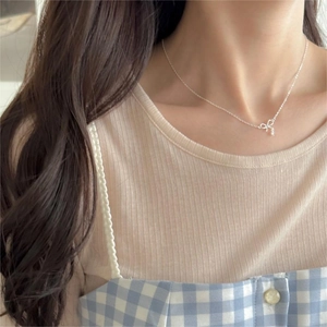 Close-up of elegant 925 silver bow pendant necklace with zircon on female model