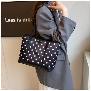 Polka dot tote bag detail showing leather strap and brand plaque on a stylish shoulder bag