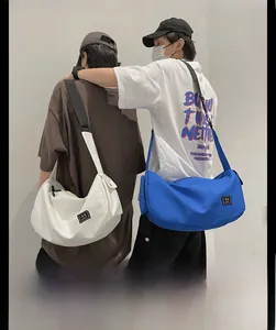 Dual models showcase large nylon crescent bags in white and blue with adjustable straps