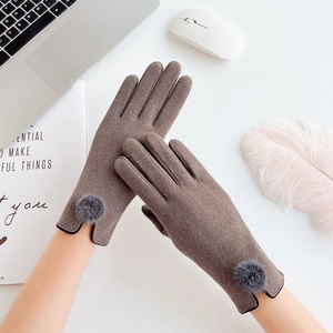 Detailed view of taupe knit touchscreen gloves with gray faux fur pom-poms on the wrist