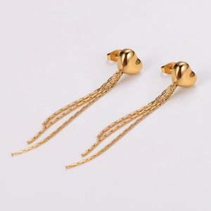 Detail shot of golden heart-shaped stud earrings with hanging tassel chains on white back
