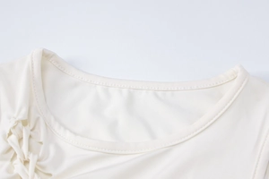 Détail de l'ensemble en maille crème avec col rond et cordon de serrage latéral sur tissu