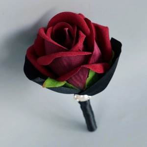 Elegant deep red velvet rose boutonniere with green leaves and pearl accents for weddings