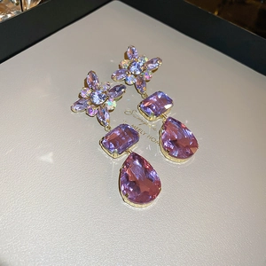Detail shot of purple crystal teardrop earrings with gold flower top and faceted gems