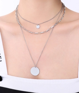 Close-up of triple-layered silver stackable necklaces set worn on a female neck