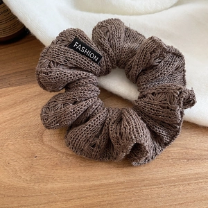 Close-up of dark brown knitted scrunchie texture with a black Fashion brand label