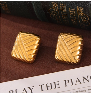 Gros plan de boucles d'oreilles rectangulaires dorées avec rayures diagonales