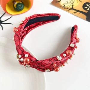 Detailed view of red Halloween headband with spider web pattern and pearl embellishments
