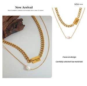Close-up of layered gold necklace with cuban chain, square pendant and pearl charm