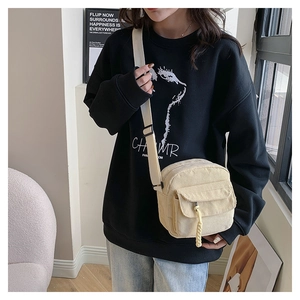 Detail of beige corduroy crossbody bag with woven rope puller and adjustable strap