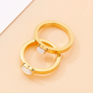 Close-up of dual gold rings with heart-shaped white cat eye stones in a polished finish