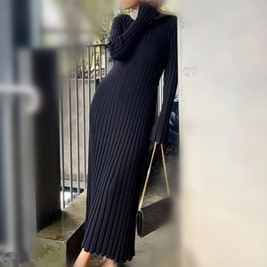 Dettaglio di un abito lungo in maglia a costine nere che mostra il drappeggio e il tessuto