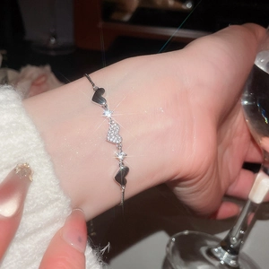 Detail of adjustable silver heart bracelet with zircon pavé on model's wrist