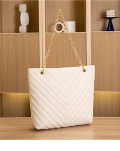 Detailed close-up of white V-quilted tote bag with premium gold chain strap on wooden desk