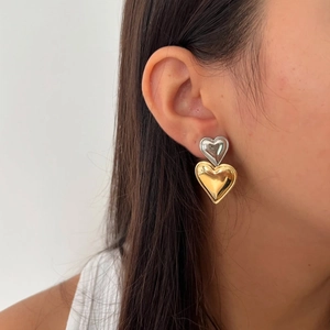 Elegant two-tone heart stud earrings in gold and silver finish worn by a model