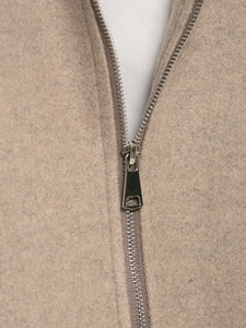 Detailed macro view of the silver metal zipper on an earth-tone wool blend bomber jacket