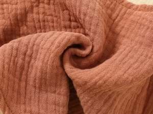 Close-up of soft reddish-brown double gauze muslin fabric with natural crinkle texture
