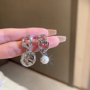 Asymmetric silver earrings with vintage coin relief and white pearl dangle accents