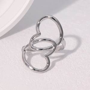 Bague ouverte coeur argenté en acier inoxydable sur fond blanc minimaliste