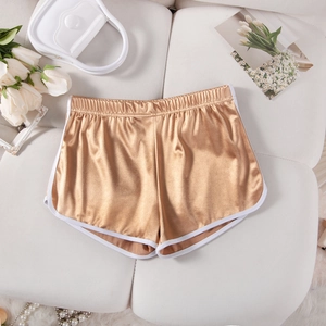 Detailed view of shiny gold sports shorts with white trim on a white decorative background