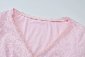 Vue détaillée du décolleté en V avec broderie de dentelle sur une robe rose