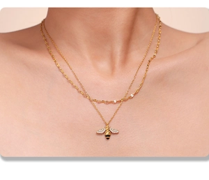 Close-up of double-layer gold necklace featuring a zircon-studded honey bee pendant