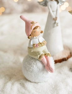 Detail of pink resin angel girl figurine with gold gift box sitting on a snowy orb base