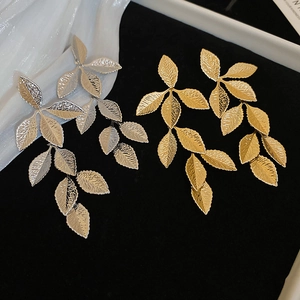 Detail showing metallic leaf-shaped earrings with natural textures in gold and silver
