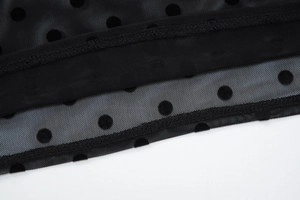 Détail du tissu en maille noire avec motifs à pois et finitions de couture précises