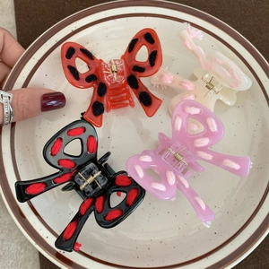 Bow-shaped acetate hair claws with woven yarn details in four vibrant colors