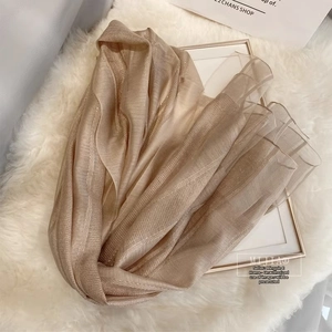 Close-up of champagne silk wool scarf texture with elegant metallic gold stripe details
