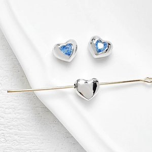 Macro shot of silver heart beads with blue zircon inlay for DIY jewelry crafts