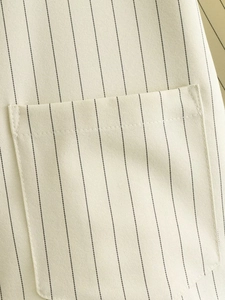 Macro shot of vertical black stripes on cream fabric with detailed pocket stitching