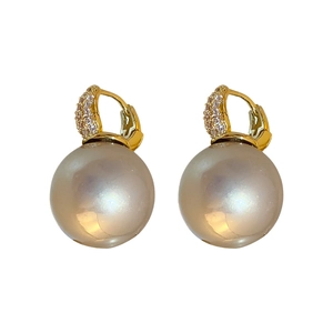 Boucles d'oreilles créoles dorées avec zircon baroque et grandes perles sur fond blanc