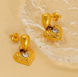 Detailed close-up of gold-plated heart earrings with hammered texture and zircon stone