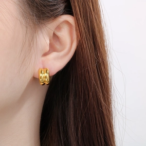Close-up of gold and silver contrast C-shaped earrings worn on a model's ear