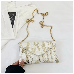 Fashionable crocodile pattern envelope crossbody bag with gold chain strap on stylish background
