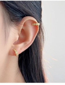 Close-up of a model wearing a gold honeycomb ear cuff and stud set with small diamonds