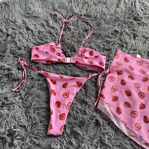 Detailed view of pink three-piece bikini set with strawberry print and mesh skirt