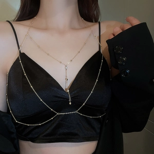 Détail d'une chaîne de corps dorée avec perles sur un mannequin en satin noir