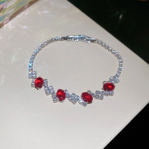 Close-up of a silver tennis bracelet with four red oval gemstones and sparkling diamonds