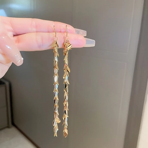 Detailed view of gold leaf sequin tassel earrings with long metallic fringe design