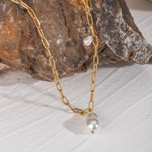Detailed shot of 18k gold plated paperclip chain with baroque pearl pendant on stone