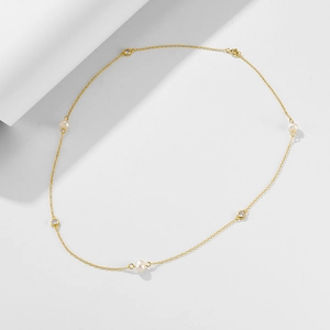 Detail view of gold chain necklace featuring natural pearls and round white zircon stones