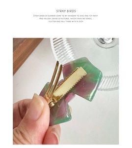 Macro detail of marble pattern hair clip with golden metal duckbill mechanism