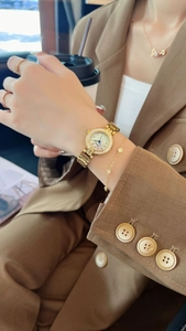 Gros plan d'une montre dorée à lunette strass avec un ensemble de bijoux sur le mannequin