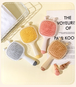 Flat lay showing four colorful cartoon bee paddle brushes with cute ears on a yellow background