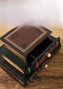 Detailed close-up of a three-tier vintage faux book jewelry box with golden line accents