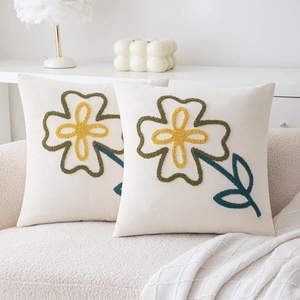 Velvet square throw pillows with embroidered floral patterns on a cozy beige sofa