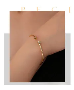 Detailed close-up of a golden C-shaped zircon open cuff bracelet on a female wrist